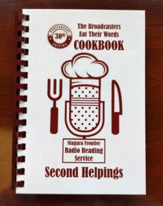 Cookbook Cover features a microphone wearing a chef's hat, holding a fork and spoon